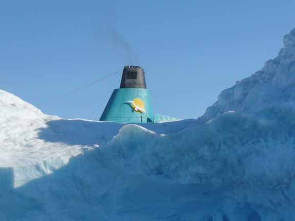 Rauchfang eines Kreuzfahrtschiffes hinter einem Eisberg